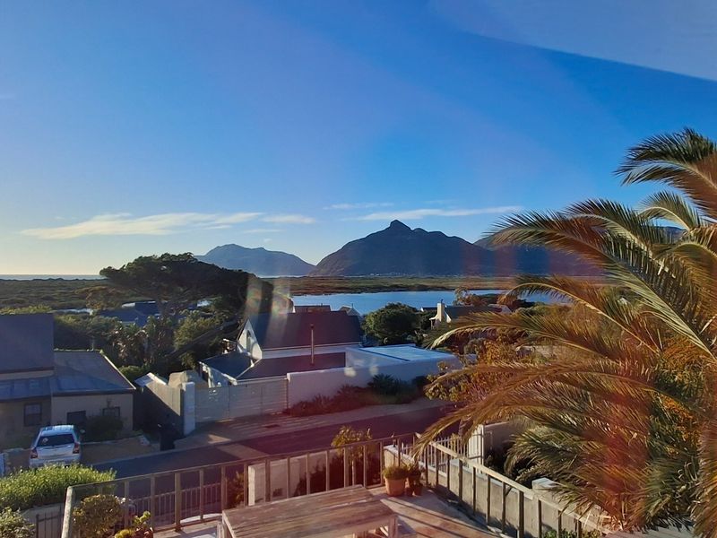 A scenic elevated view overlooking the surrounding neighborhood, coastal landscape, and distant mountains, captured from a balcony.