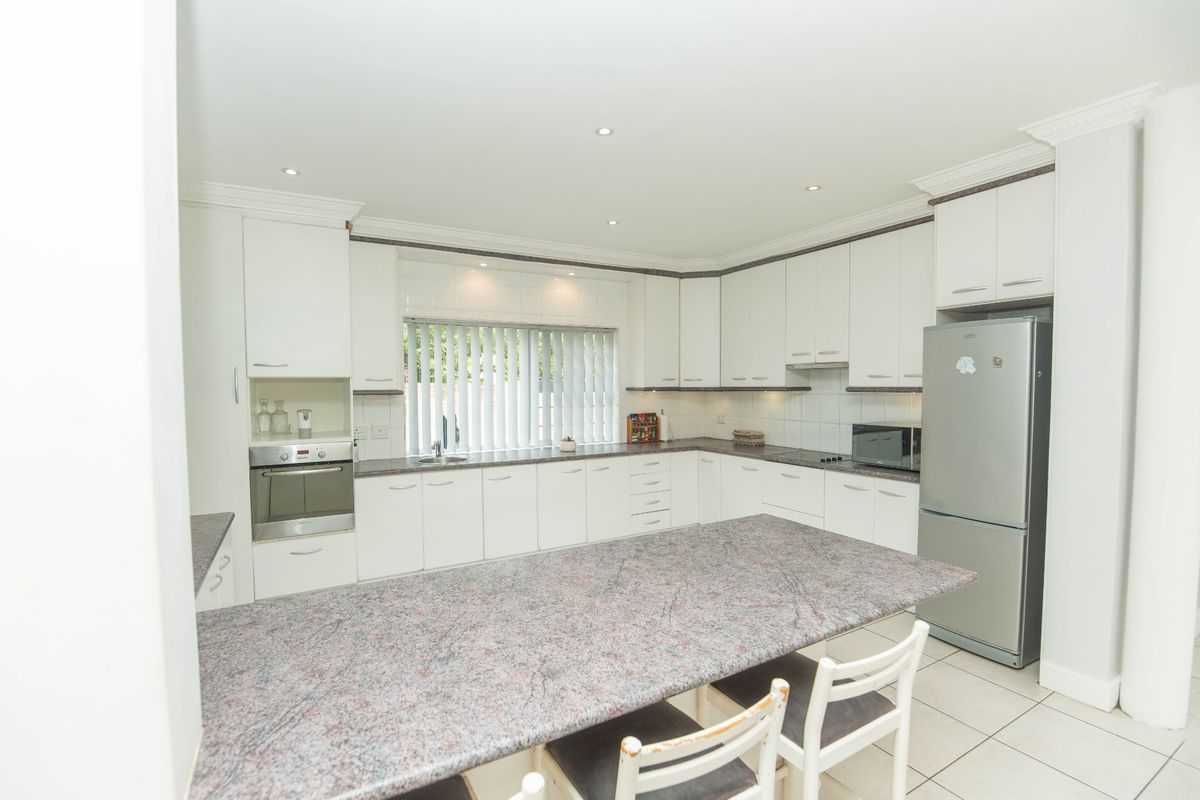 A well-maintained kitchen featuring white cabinetry, granite countertops, integrated appliances, and tiled flooring with recessed lighting.