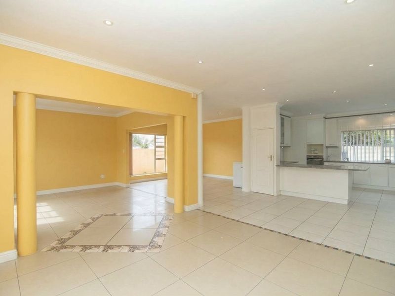Spacious open-plan living and kitchen area featuring tiled floors, recessed lighting, and a functional kitchen layout with built-in cabinetry.