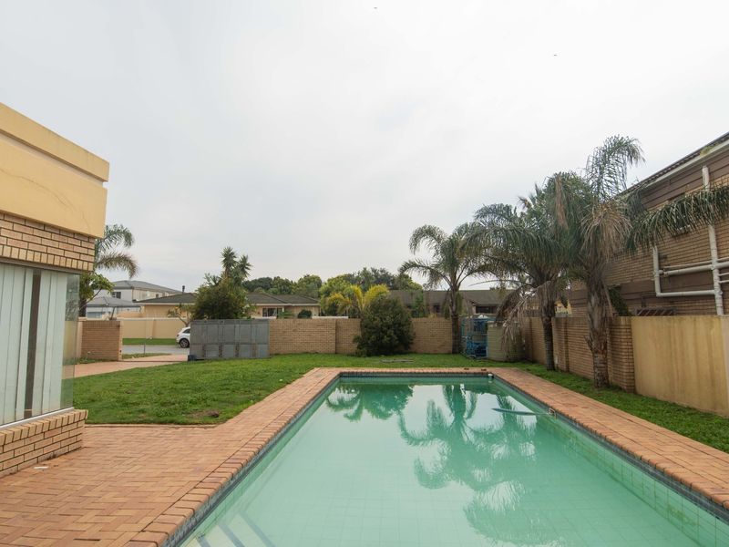 A rear garden area featuring a swimming pool with brick paving and perimeter boundary walls.