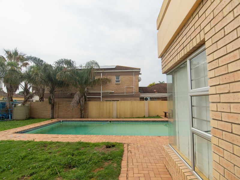 Outdoor pool area featuring a swimming pool, brick paved surround, and boundary walling, set within a private garden space.
