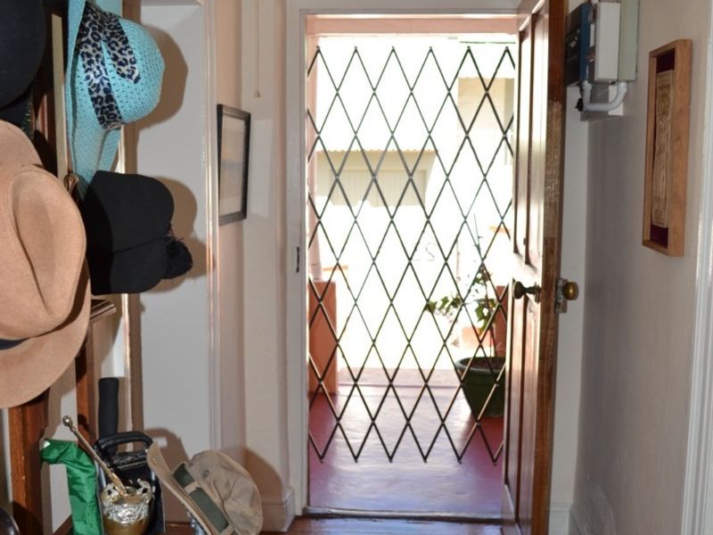 Entrance hallway featuring polished timber flooring and a secure metal gate leading to the exterior.