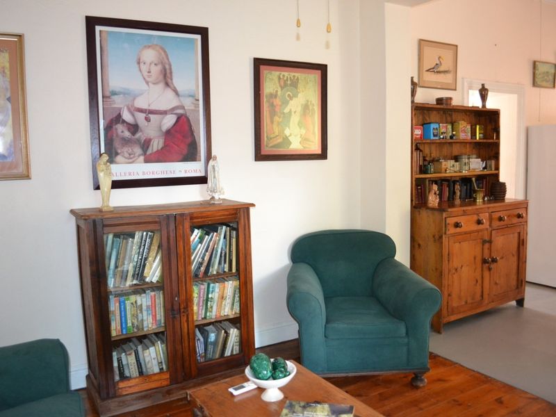 A living room area featuring warm hardwood flooring and neutral wall finishes, providing a comfortable and traditional living space.