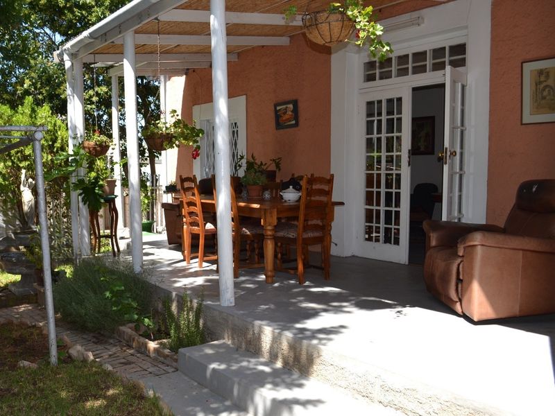 A covered outdoor patio area featuring a timber pergola, concrete flooring, and direct access to the home through classic french doors.