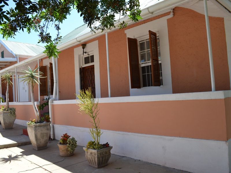 A charming front facade featuring a covered veranda, classic sash windows with timber shutters, and a well-maintained exterior finish.