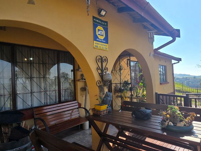 Covered patio area featuring arched masonry pillars, tiled flooring, and security features, offering an outdoor space with views.