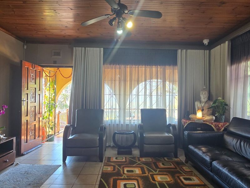 A living room featuring a timber-paneled ceiling, ceiling fan, and tiled flooring, with direct access to an outdoor patio area.
