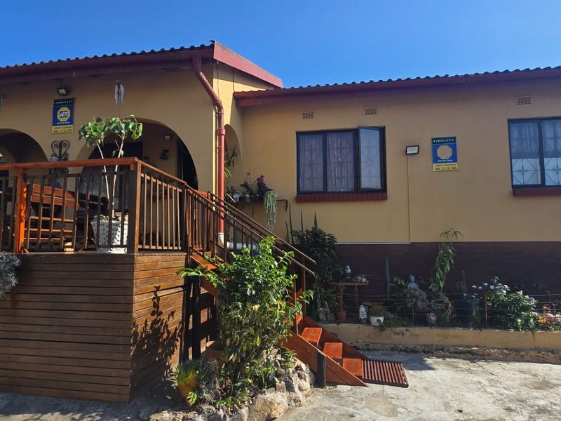 Front elevation of a single-story house featuring a raised timber deck, staircase, and security-fitted windows under a tiled roof.