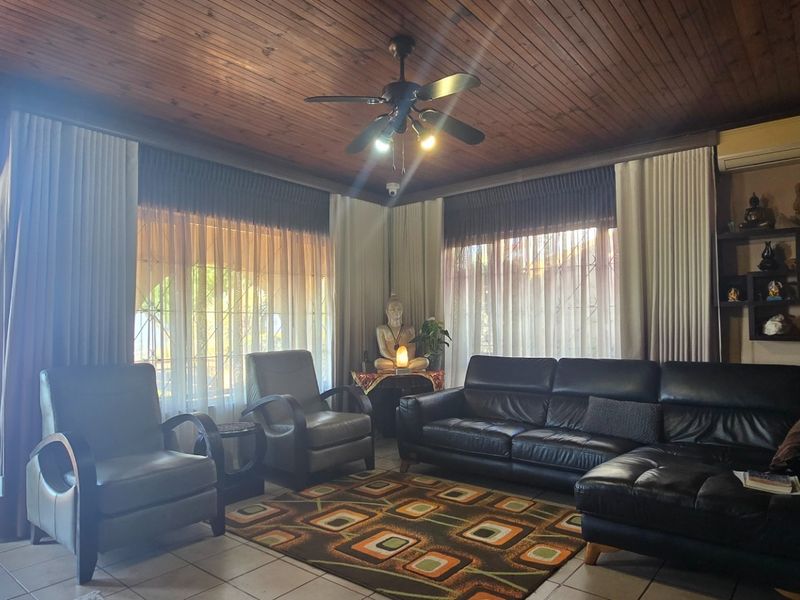 A spacious living room featuring a timber-clad ceiling, ceiling fan, split-system air conditioning, and built-in wall shelving, with direct access to an outdoor balcony.