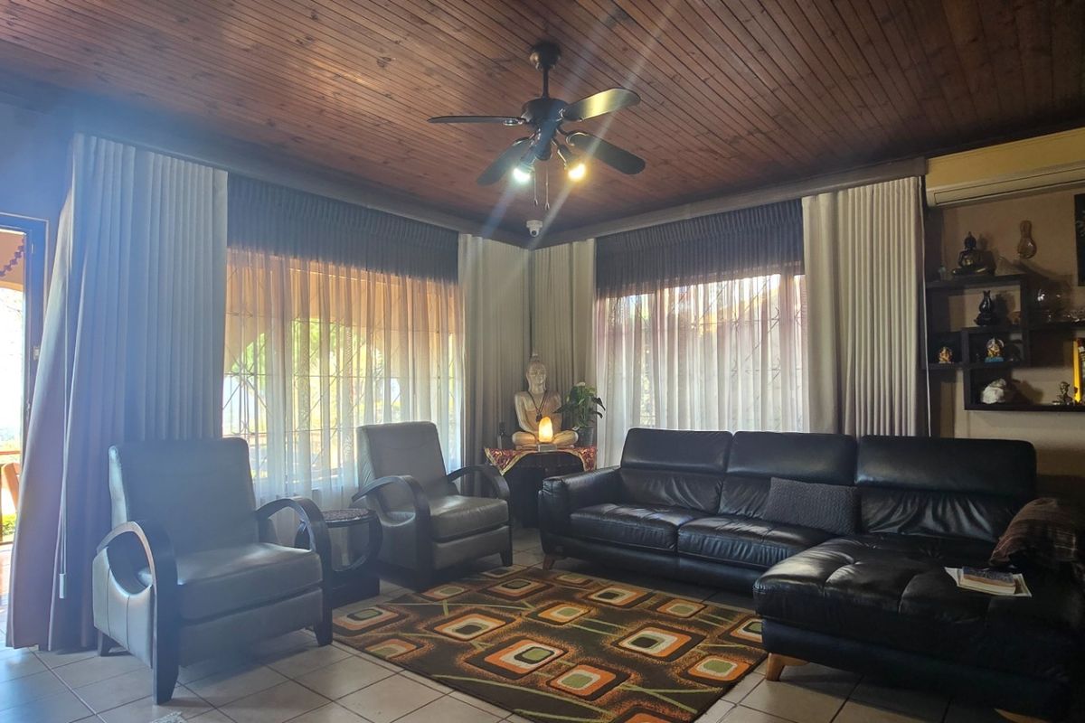 A spacious living room featuring a timber-clad ceiling, ceiling fan, split-system air conditioning, and built-in wall shelving, with direct access to an outdoor balcony.