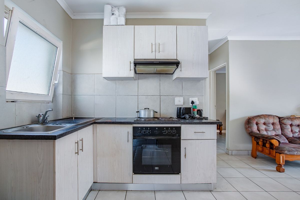 A functional kitchen featuring light-toned built-in cabinetry, dark laminate countertops, a built-in oven with hob, and a tiled backsplash.
