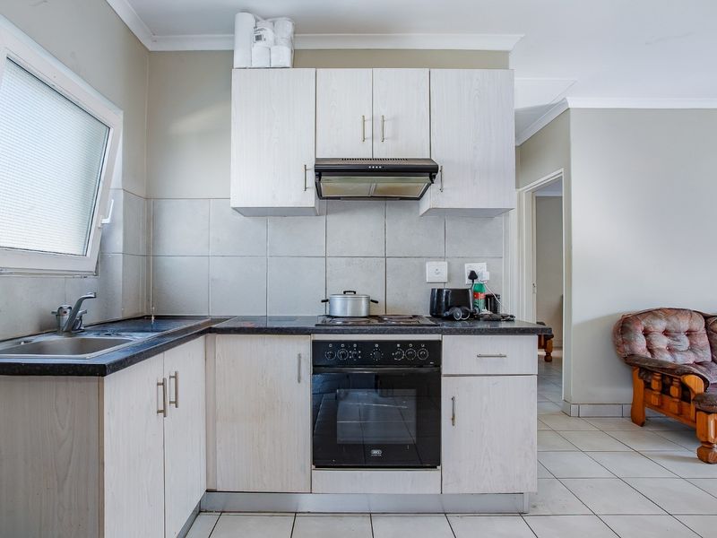 A functional kitchen featuring light-toned built-in cabinetry, dark laminate countertops, a built-in oven with hob, and a tiled backsplash.