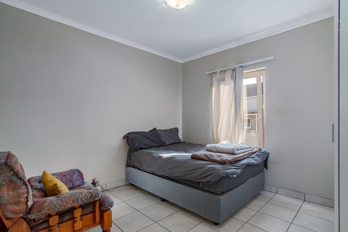 A functional bedroom featuring tiled flooring, neutral wall tones, and a built-in cupboard with direct access to an outdoor area.