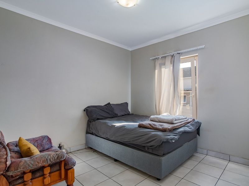 A functional bedroom featuring tiled flooring, neutral wall tones, and a built-in cupboard with direct access to an outdoor area.