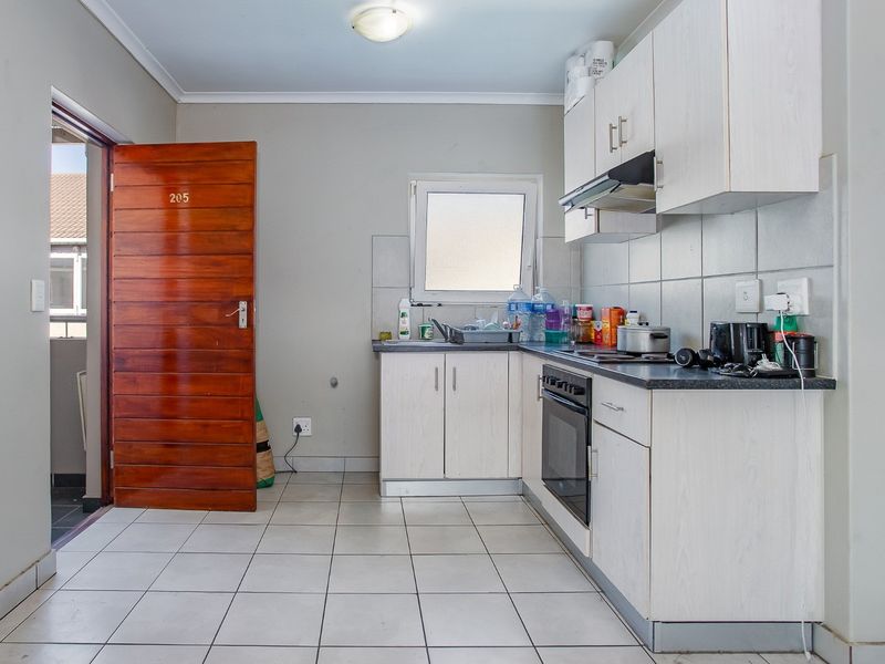 Functional kitchen featuring built-in cabinetry, laminate countertops, integrated oven, extractor fan, and tiled flooring with direct access to an exterior balcony.