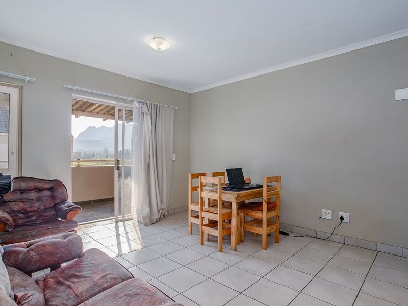 A living room featuring ceramic floor tiles and a sliding glass door providing access to a balcony with mountain views.