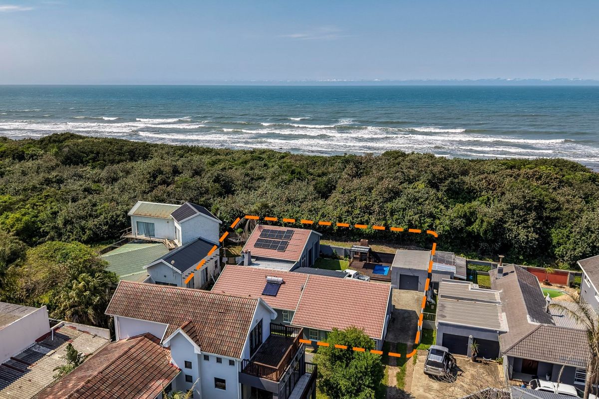 Aerial view of a coastal property featuring a tiled roof, solar panels, private swimming pool, and garage, situated near the ocean.
