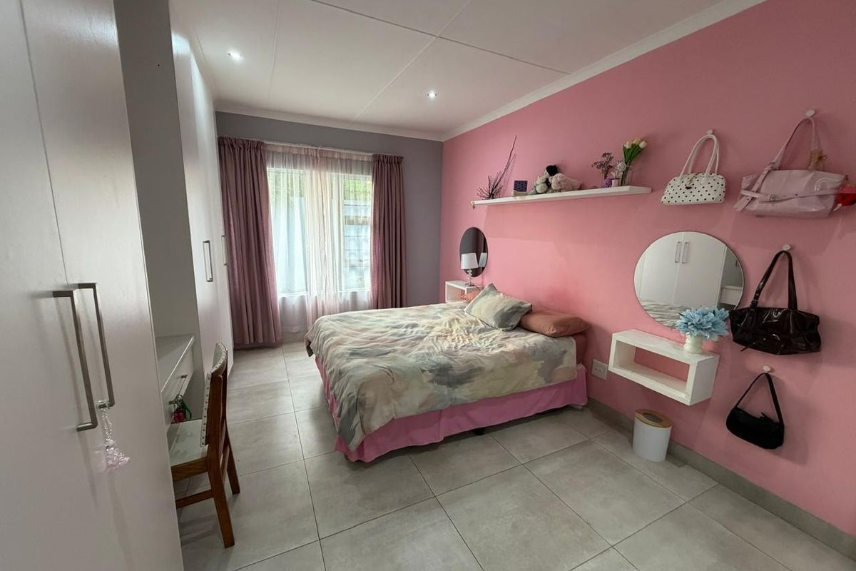 A well-maintained bedroom featuring tiled flooring, built-in cupboards, and recessed ceiling lighting, offering a clean and functional living space.
