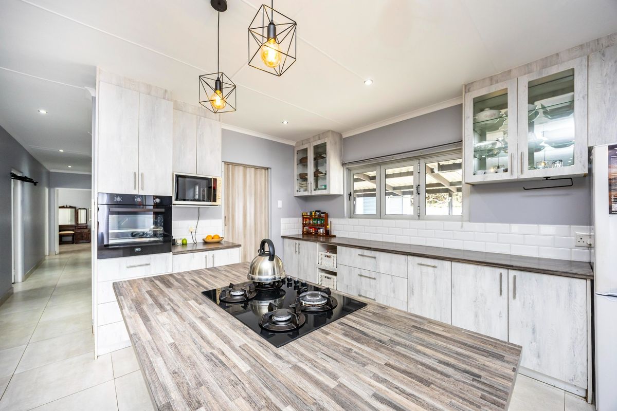 Modern kitchen featuring a central island with a gas hob, built-in oven, microwave, and ample cabinetry with a stylish subway tile backsplash.