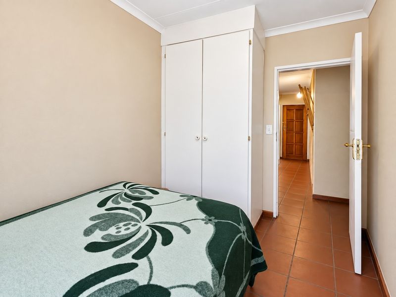 A bedroom featuring tiled flooring, neutral wall finishes, and a built-in wardrobe, with direct access to the hallway.