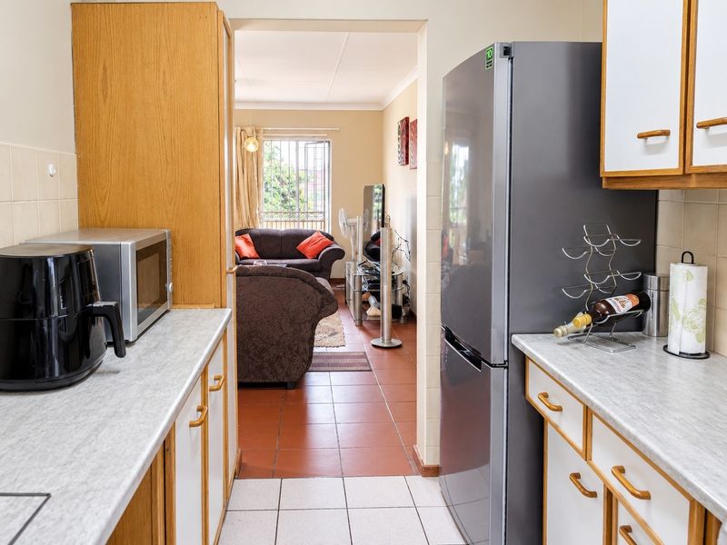 A functional kitchen featuring laminate countertops, built-in cabinetry, and tiled flooring, with a direct view into the adjacent living area.