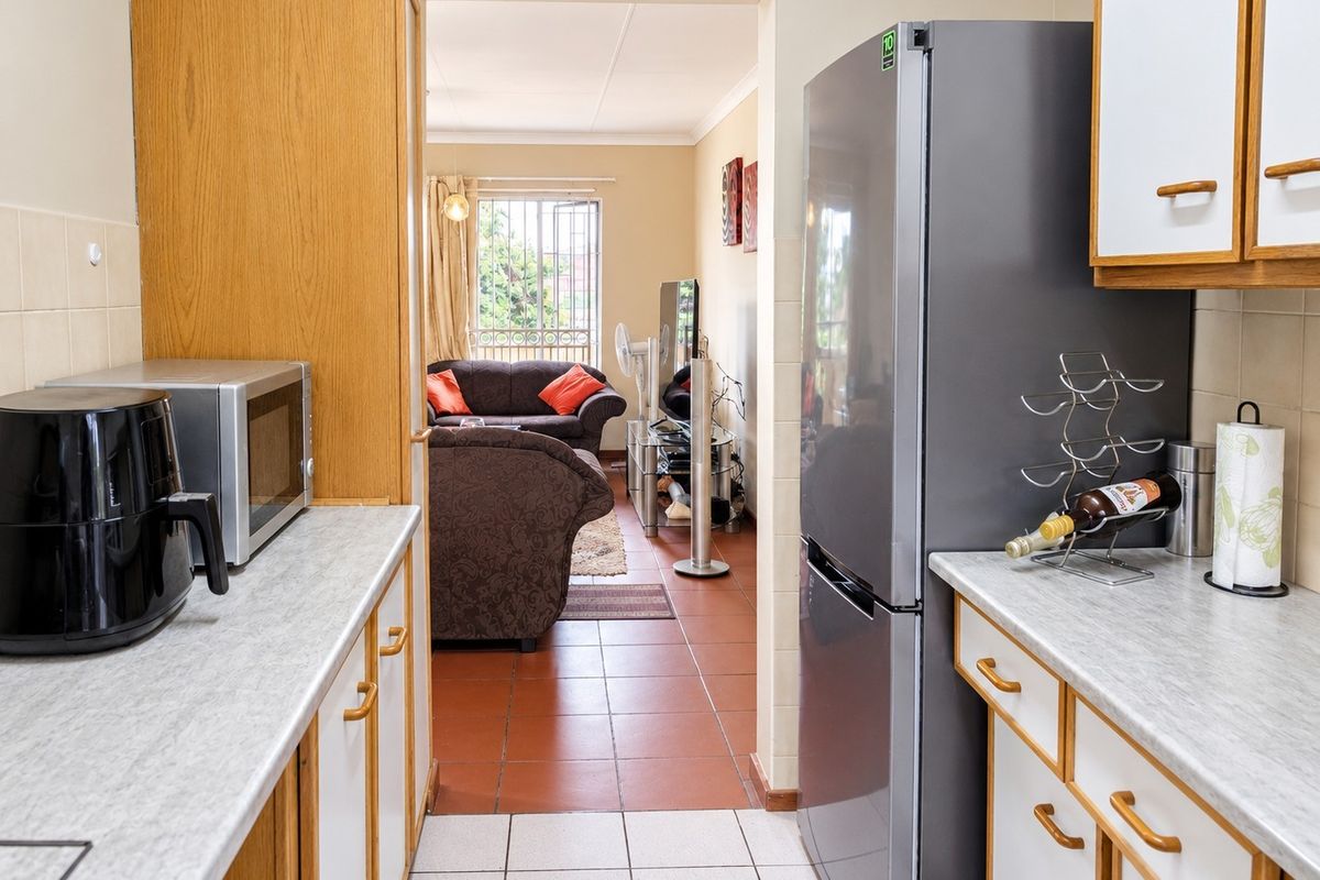 A functional kitchen featuring laminate countertops, built-in cabinetry, and tiled flooring, with a direct view into the adjacent living area.