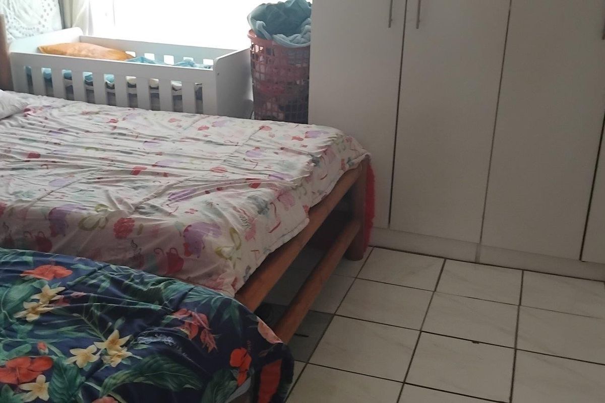 A bedroom featuring tiled flooring and built-in cupboards, providing functional storage space.