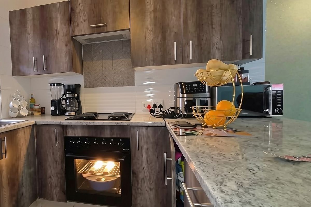 Modern kitchen featuring wood-grain cabinetry, stone-look countertops, built-in oven, gas hob, and a tiled backsplash.
