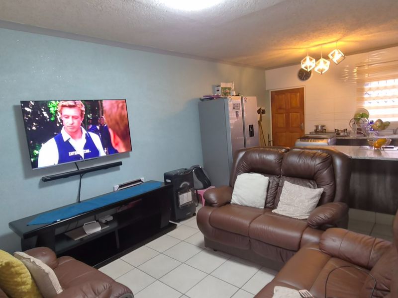 Open plan living area featuring tiled flooring and a functional kitchen with a breakfast bar and built-in cabinetry.