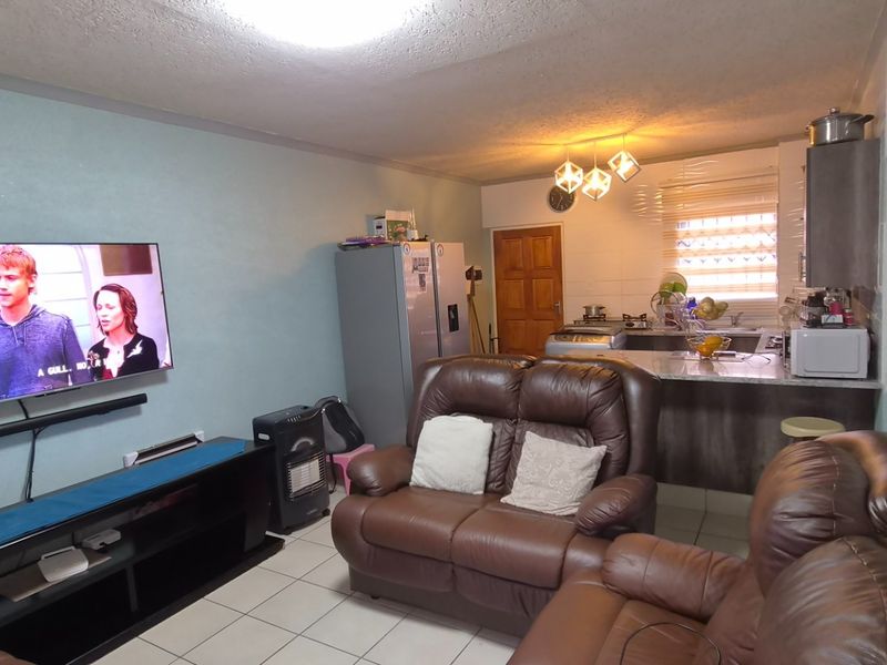 Open plan living area featuring a combined kitchen and lounge space with tiled flooring and functional cabinetry.