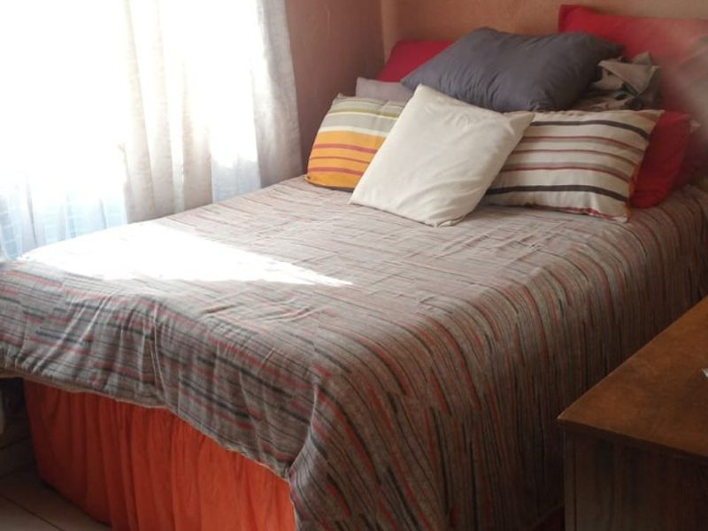 A compact bedroom featuring tiled flooring and decorative ceiling cornicing, requiring cosmetic updates to the wall finishes.