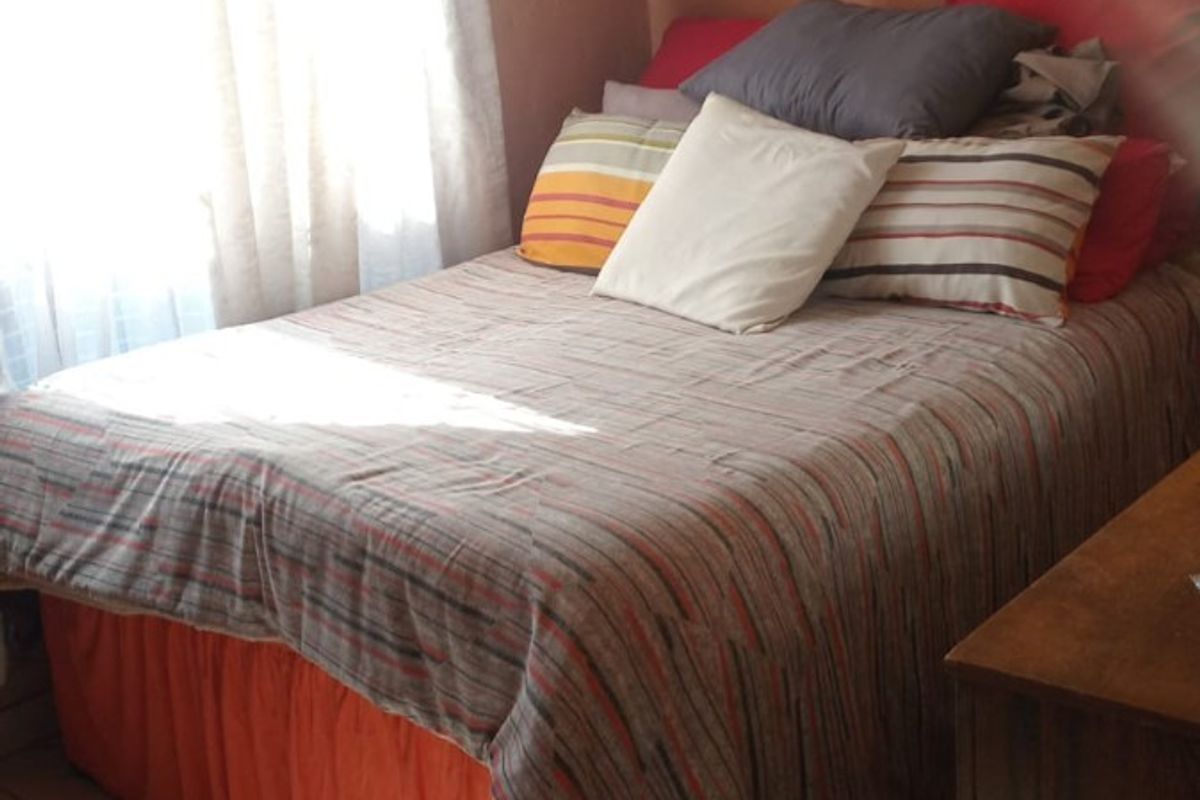 A compact bedroom featuring tiled flooring and decorative ceiling cornicing, requiring cosmetic updates to the wall finishes.