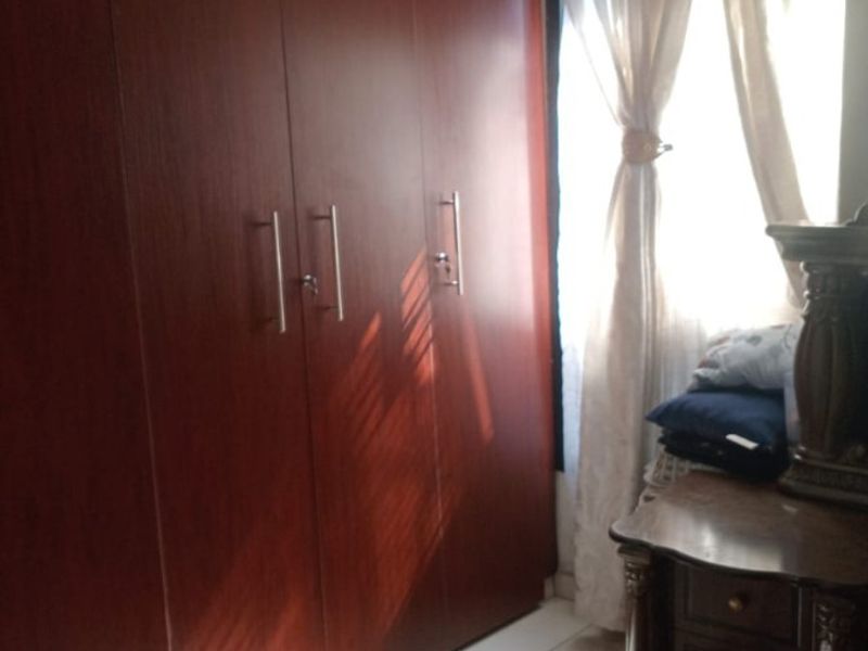 A bedroom featuring large dark wood built-in wardrobes and light-colored floor tiles, providing ample storage space.