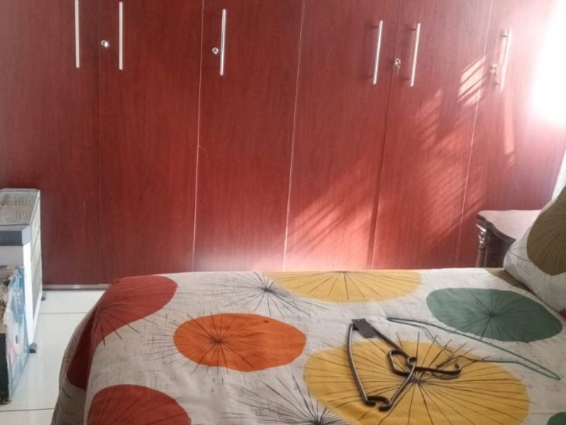 A bedroom featuring extensive floor-to-ceiling built-in wooden cupboards providing ample storage space.