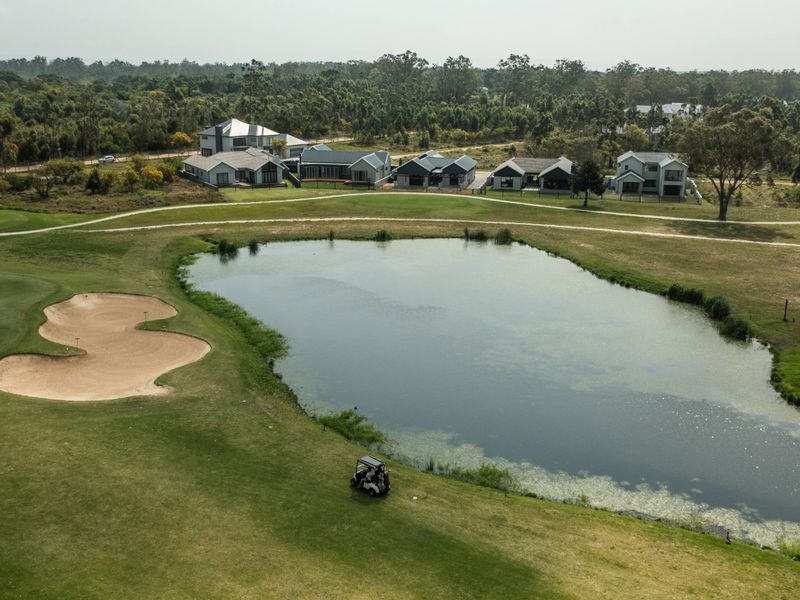 Aerial view of a residential estate overlooking a golf course with a central water hazard and sand bunker.