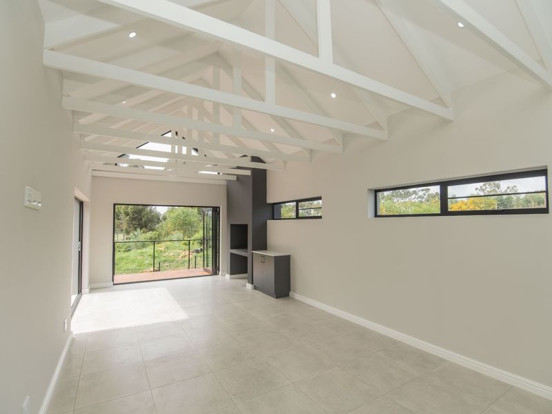 Spacious living area featuring a high vaulted ceiling with exposed trusses, tiled flooring, built-in fireplace, and large bi-fold doors opening to the outdoors.