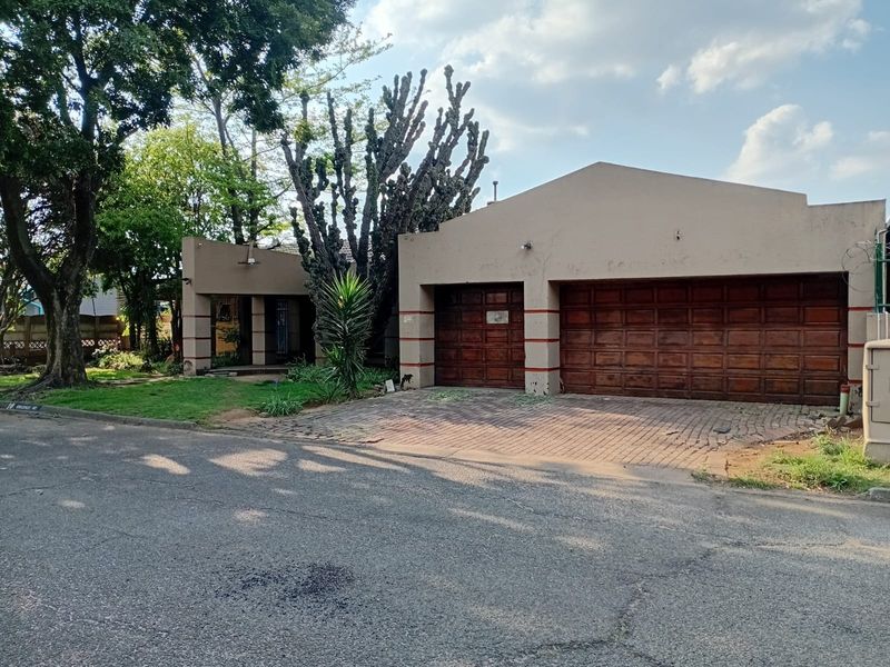 Front exterior view of the property featuring a double garage with wooden doors and a paved driveway.