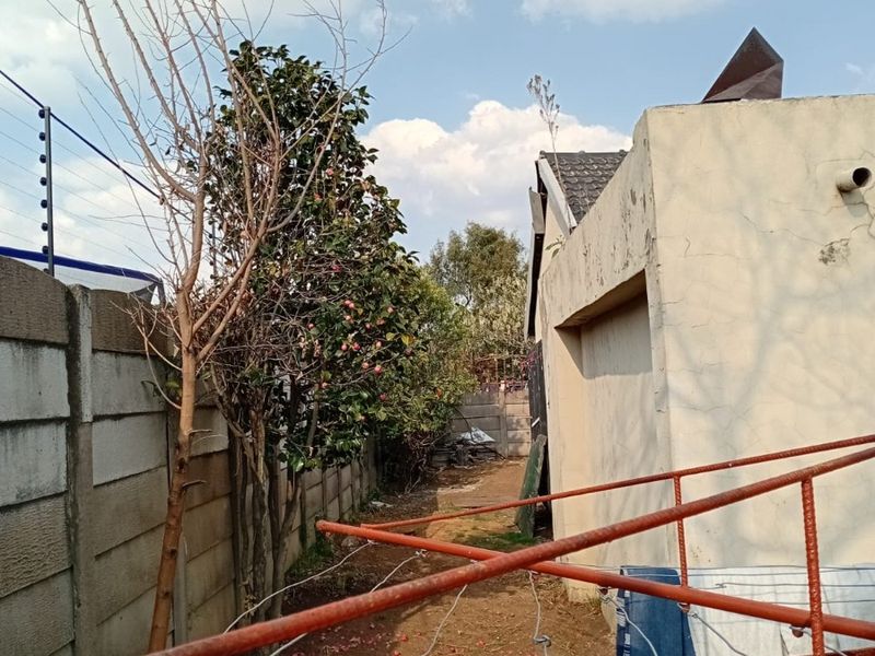 Rear exterior area featuring a precast concrete boundary wall with electric fencing, a metal washing line, and weathered exterior wall finishes.