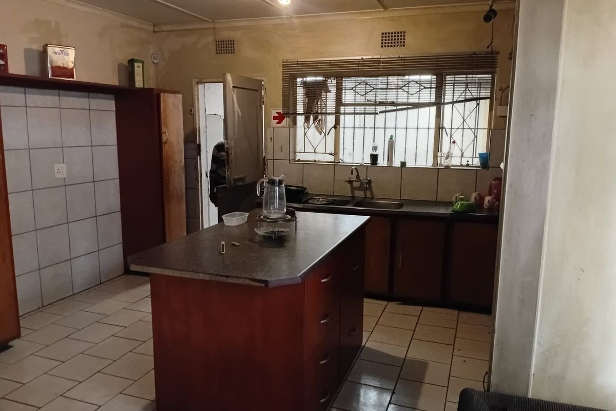 A dated kitchen featuring a central island, tiled flooring, and built-in cabinetry, offering significant potential for modernization and renovation.