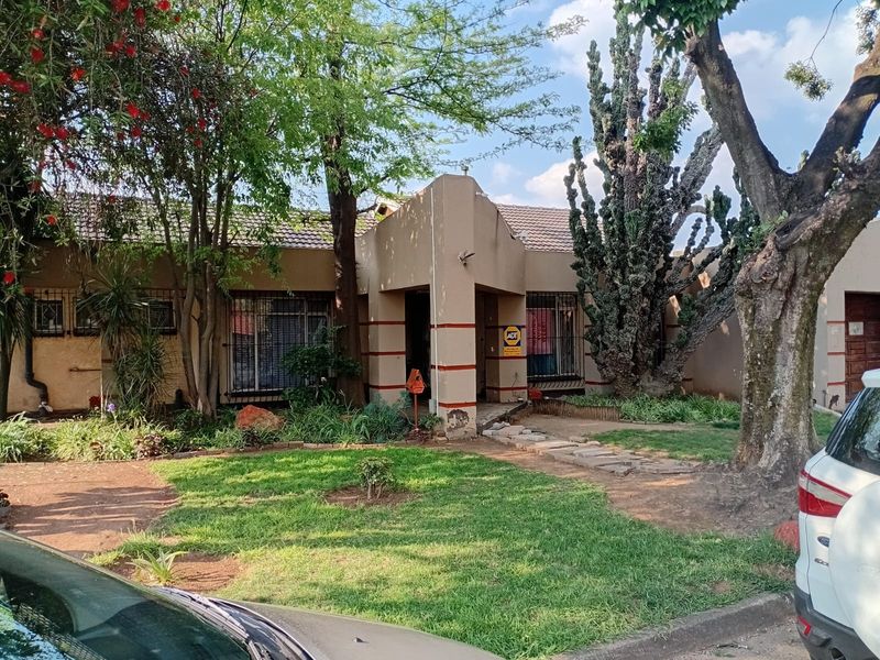 Front elevation of a single-story house featuring a tiled roof, security bars on windows, and a paved entrance path with established garden landscaping.