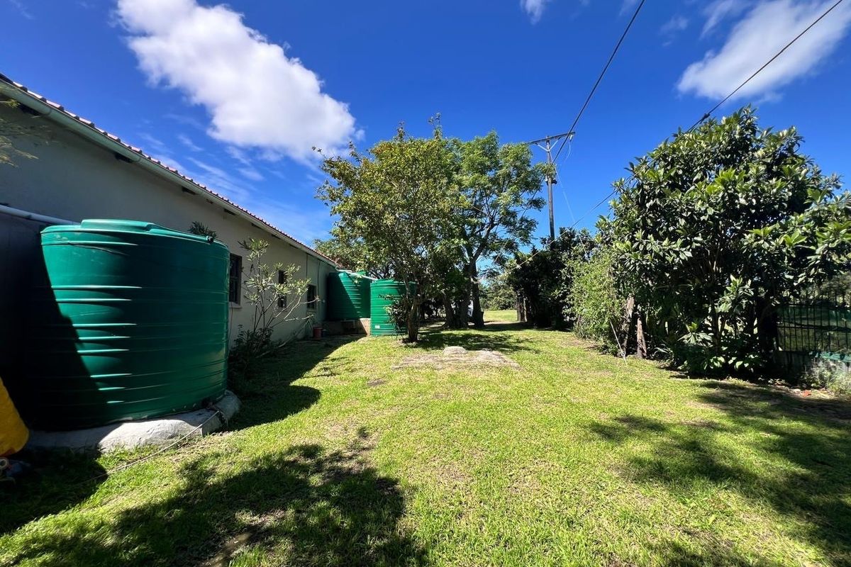 Rear garden area featuring large green water storage tanks, established trees, and a well-maintained lawn space.
