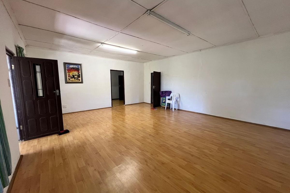 A spacious, empty living area featuring light-toned laminate flooring and functional overhead lighting, offering a blank canvas for interior design updates.