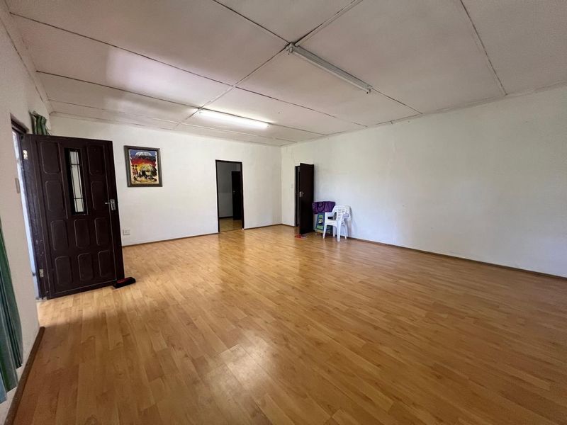 A spacious, empty living area featuring light-toned laminate flooring and functional overhead lighting, offering a blank canvas for interior design updates.