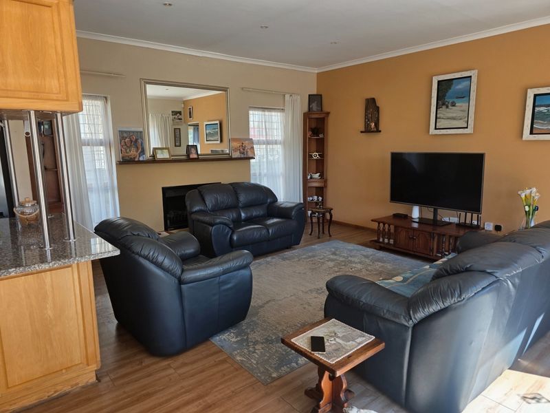 Spacious open-plan living area featuring laminate flooring, a fireplace, and a kitchen breakfast bar with granite countertops.
