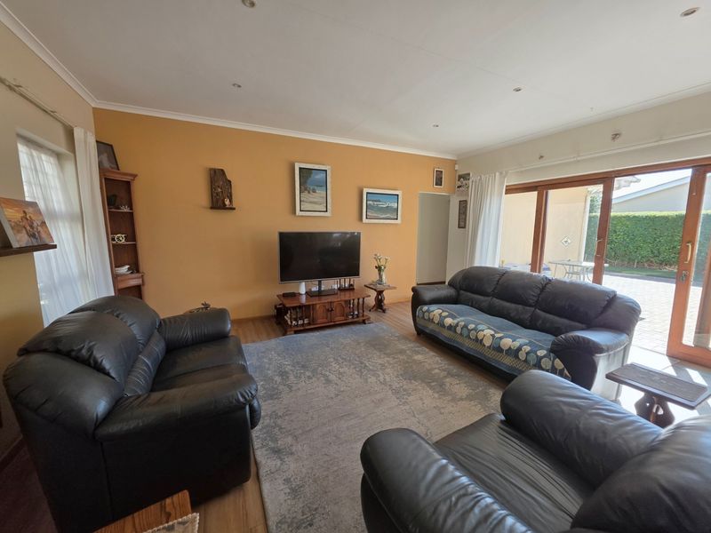 A spacious living room featuring laminate flooring, recessed lighting, and large sliding glass doors that provide direct access to the outdoor patio area.