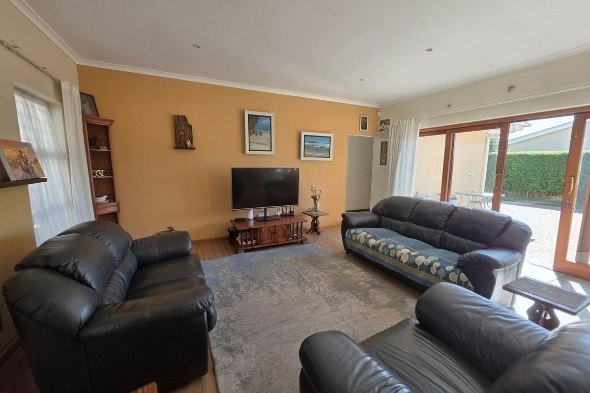 A spacious living room featuring laminate flooring, recessed lighting, and large sliding glass doors that provide direct access to the outdoor patio area.