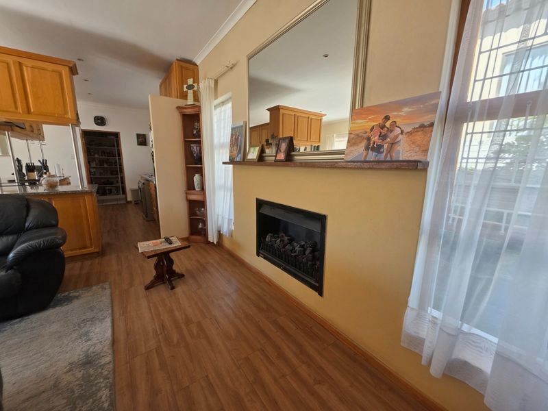 Open plan living area featuring a built-in fireplace, laminate flooring, and a connected kitchen with wooden cabinetry and granite countertops.