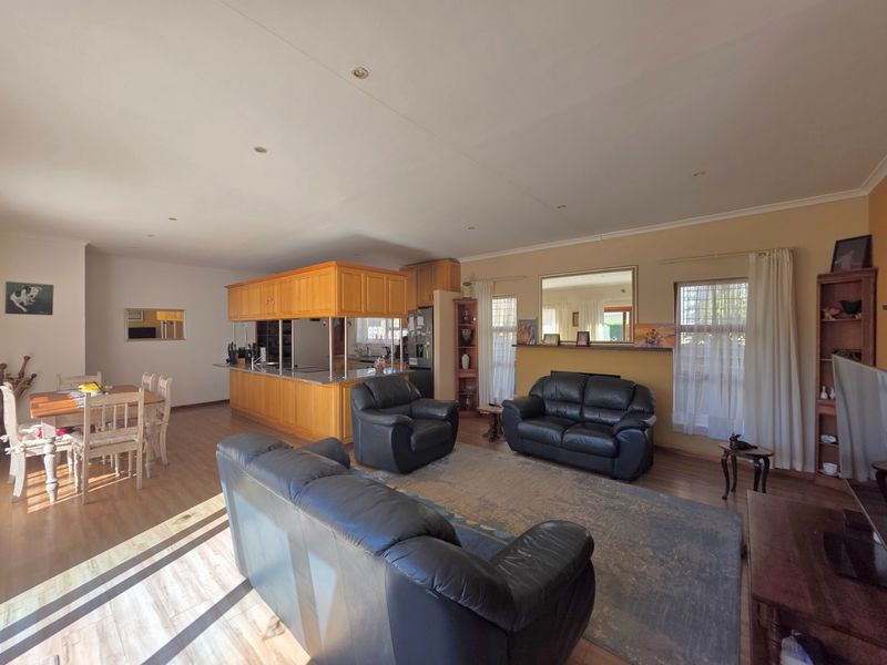 Spacious open-plan living and dining area featuring a large kitchen with wooden cabinetry, granite countertops, and laminate flooring throughout.