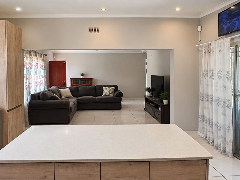 Open-plan living area featuring a modern kitchen island, tiled flooring, and large sliding glass doors providing access to the exterior.