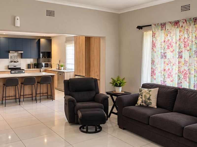 Modern open-plan living area featuring a contemporary kitchen with a central island, sleek cabinetry, and polished tiled flooring throughout the space.